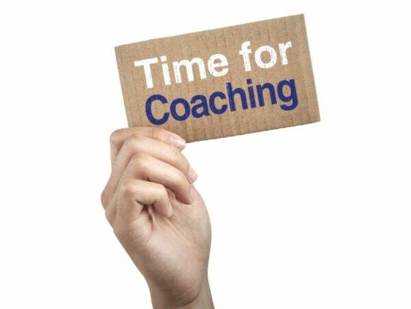 Main qui tient un carton avec le texte "time for coaching"
